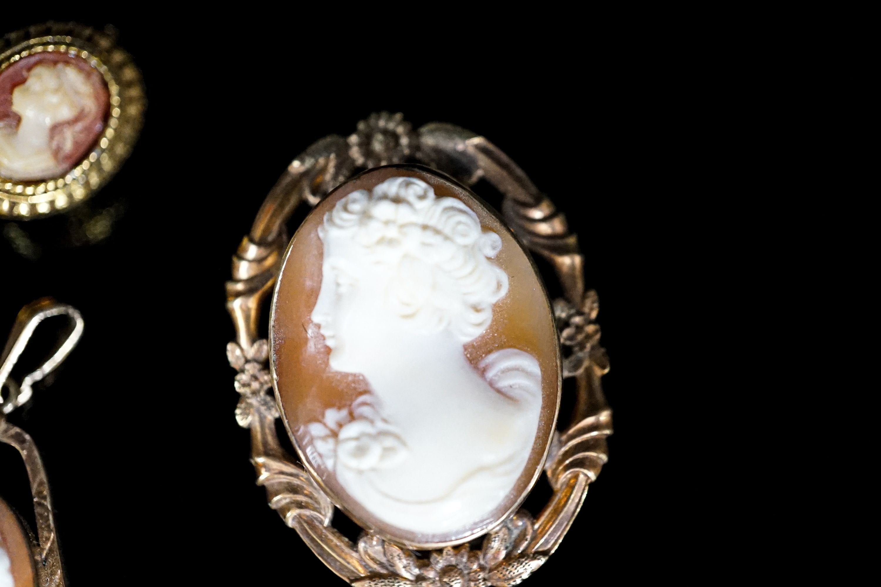 Two mounted cameo shell pendants, one with brooch attachment and a gilt metal cameo pin.